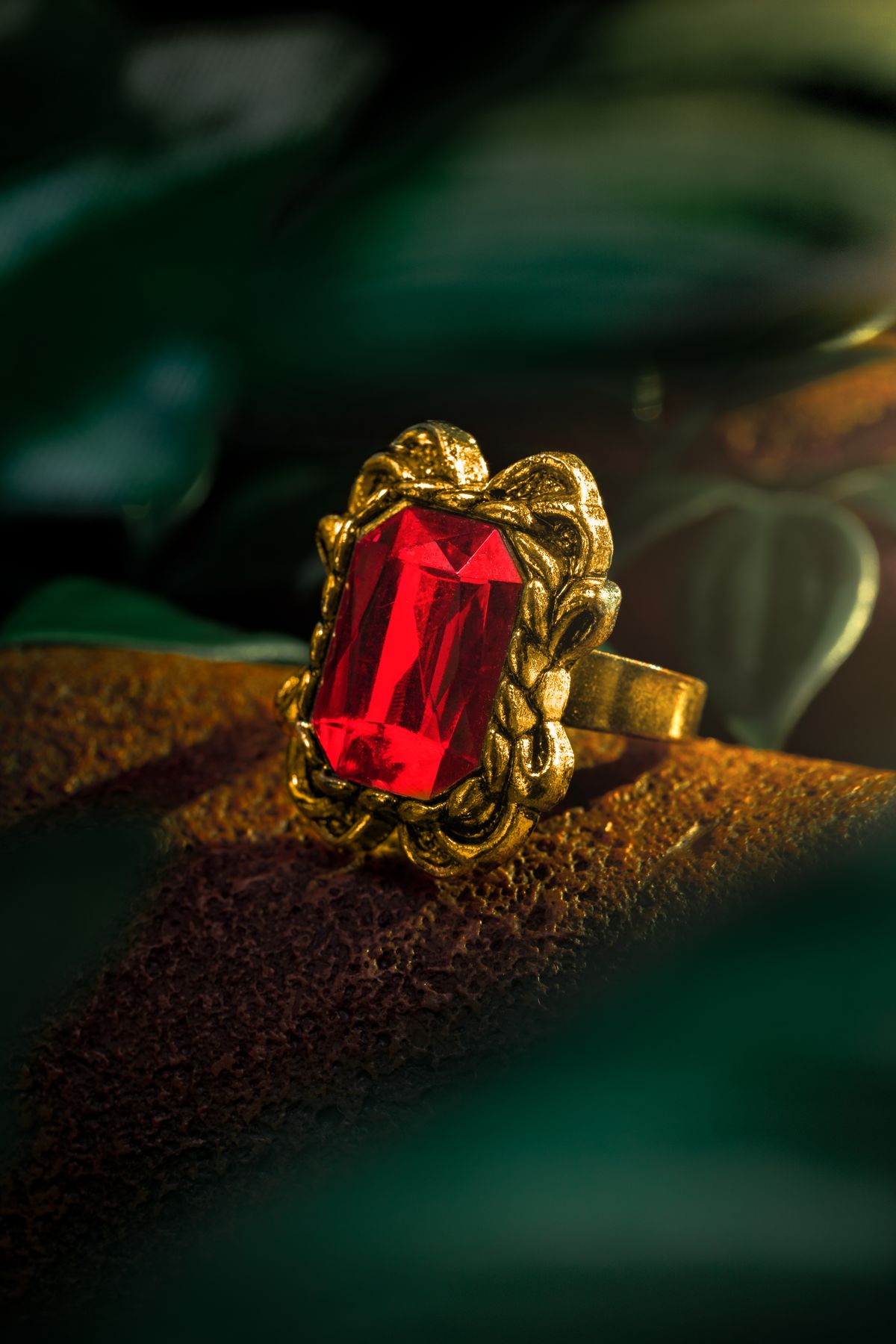 Ornate gold ring set with a deep red gemstone